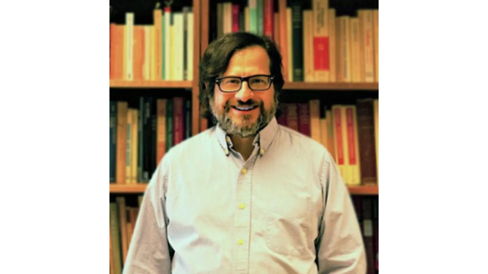 Mike Jacovides by a bookshelf