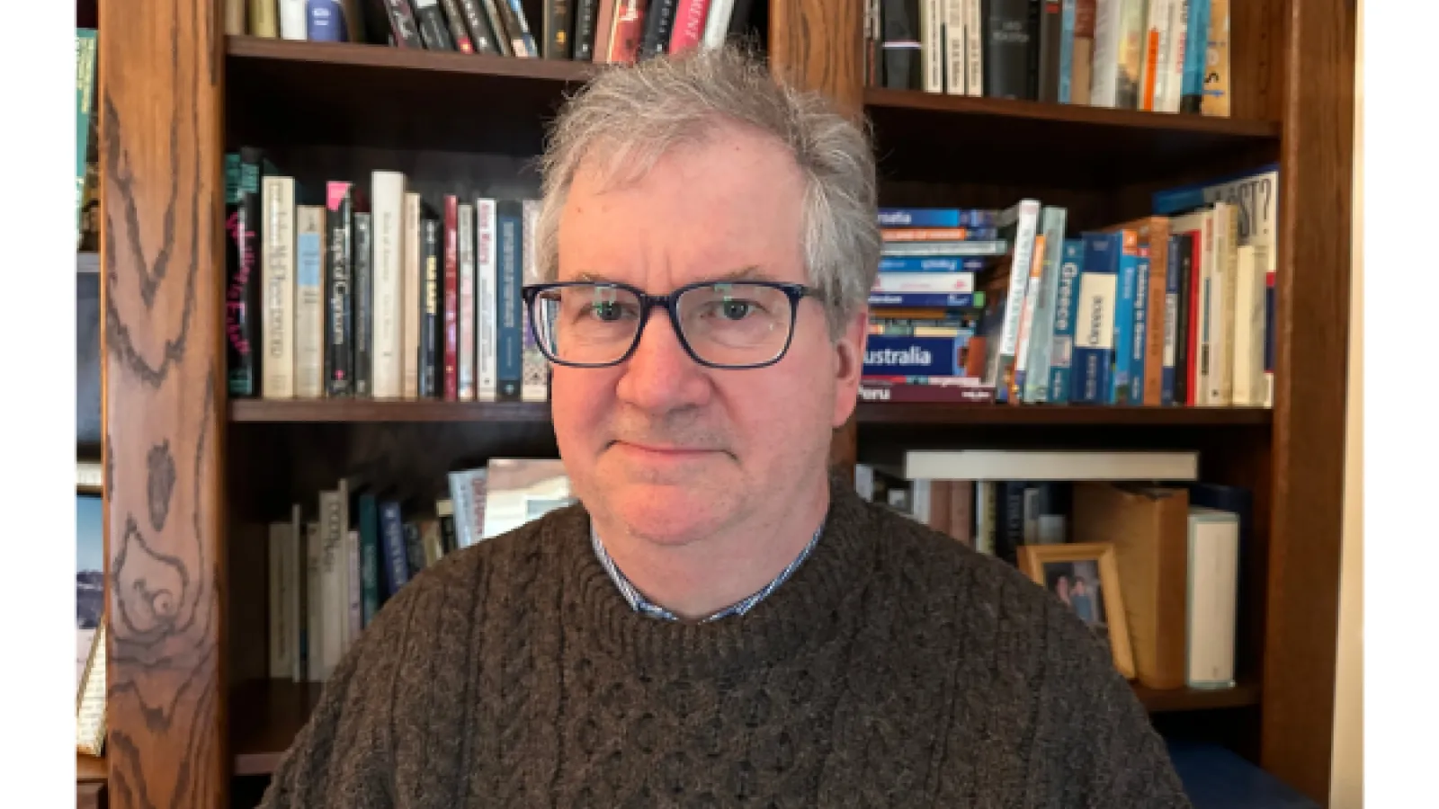 Professor D'Arms in front of a bookshelf