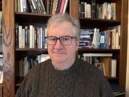 Professor D'Arms in front of bookshelf