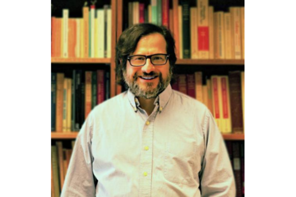 Mike Jacovides by a bookshelf