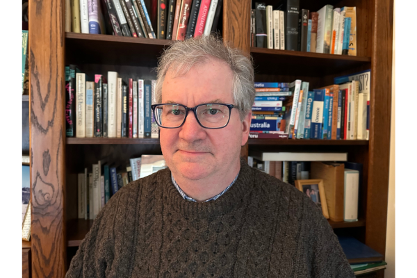 Professor D'Arms in front of a bookshelf