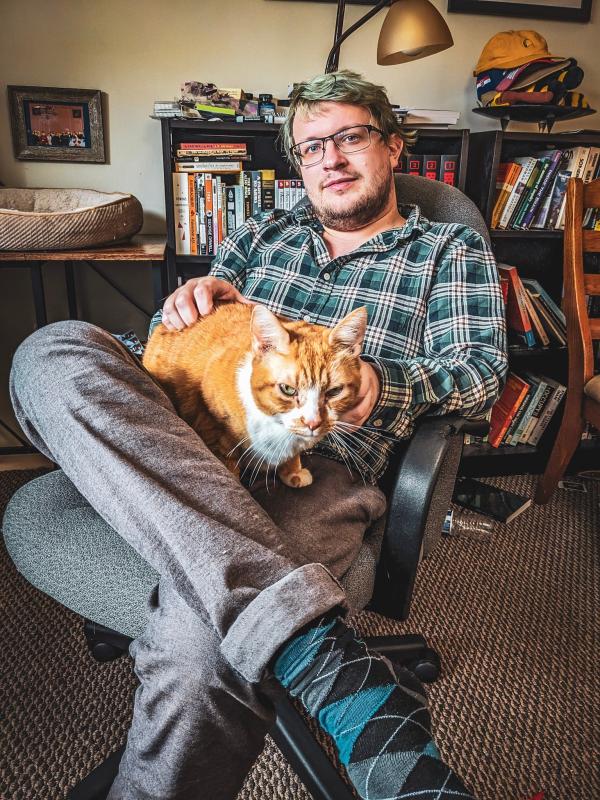 Seated person with a majestic orange cat in lap